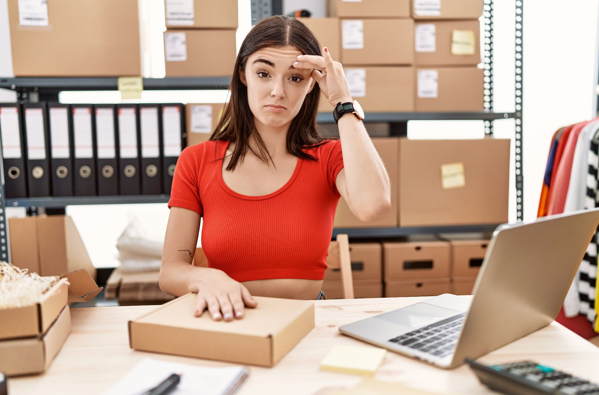 Young panic woman preparing order working at storehouse worried and stressed about a problem with hand on forehead, nervous and anxious for crisis